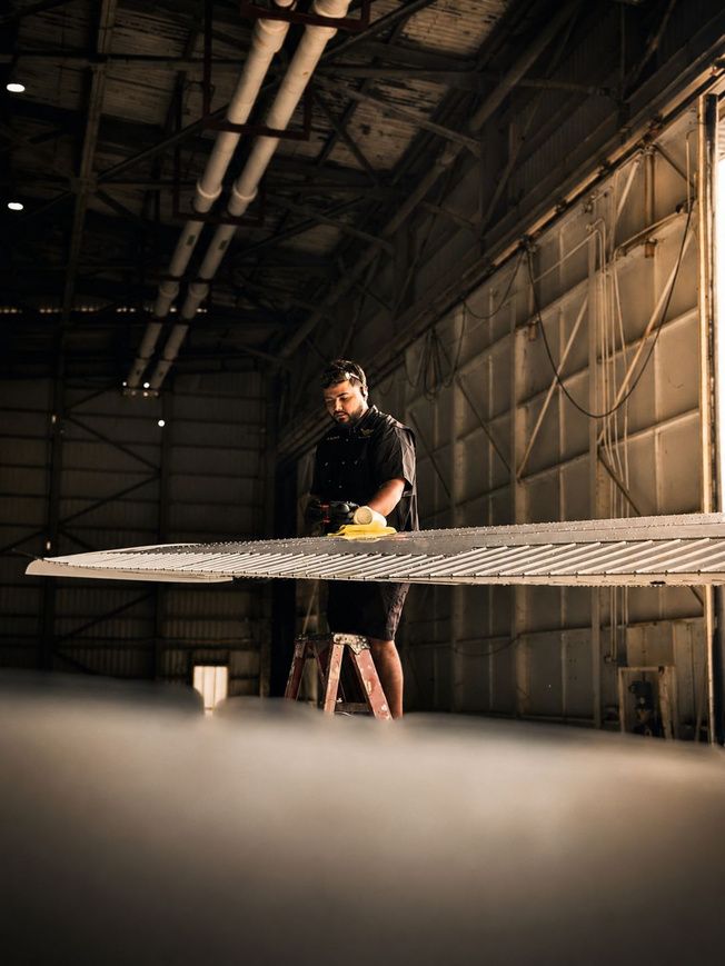 Technician sanding an aircraft wing in the hangar